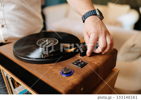 Hand lowering tonearm on vinyl record player, cozy home audio setup Hand lowering tonearm on vinyl record player, cozy home audio setup 133148161