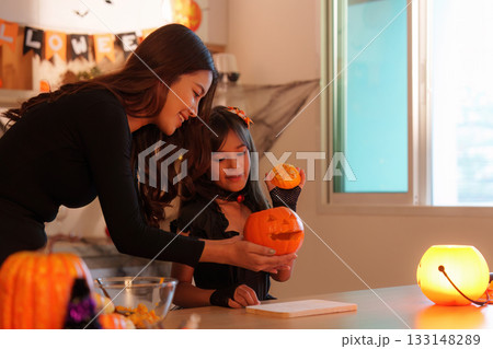 Halloween Pumpkin Fun. Mother and daughter showcasing their carved pumpkin. 133148289