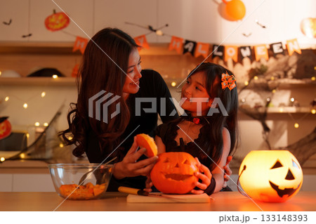 Halloween Fun: Mother and Daughter Carving Pumpkins Together 133148393