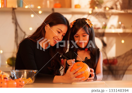 Halloween Fun: Mother and Daughter Carving Pumpkins Together 133148394
