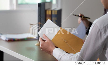 Document Review. A client holding a legal envelope while consulting with a lawyer. Document Review. A client holding a legal envelope while consulting with a lawyer. 133148484