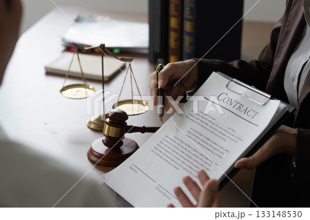 Contract Signing. Lawyer presenting contract to client with gavel on desk. 133148530