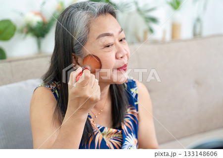 Makeup Application. Mature woman applying blush with a brush in front of a mirror. Makeup Application. Mature woman applying blush with a brush in front of a mirror. 133148606