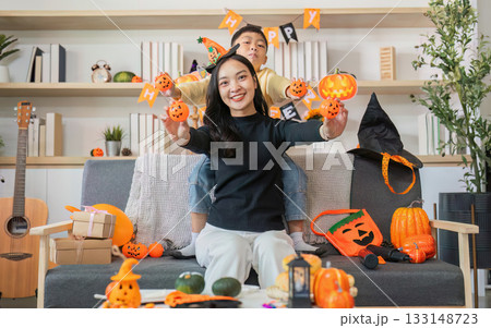 Halloween Celebration. A joyful woman and child surrounded by festive decorations and pumpkins. Halloween Celebration. A joyful woman and child surrounded by festive decorations and pumpkins. 133148723