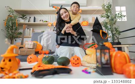 Halloween Celebration. A joyful mother and son enjoying festive decorations and activities at home. Halloween Celebration. A joyful mother and son enjoying festive decorations and activities at home. 133148802
