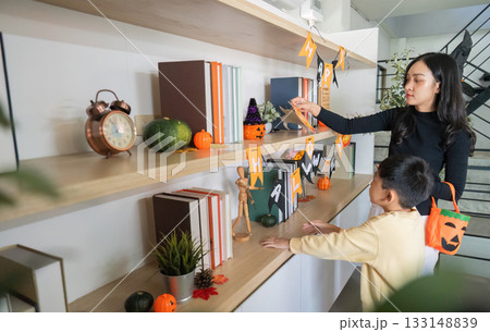 Halloween Celebration. A mother and son decorating their home with festive Halloween decorations. 133148839