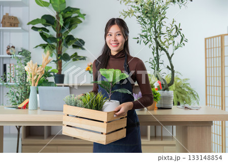 Plant Shop. Woman carrying a wooden crate filled with various plants. Plant Shop. Woman carrying a wooden crate filled with various plants. 133148854
