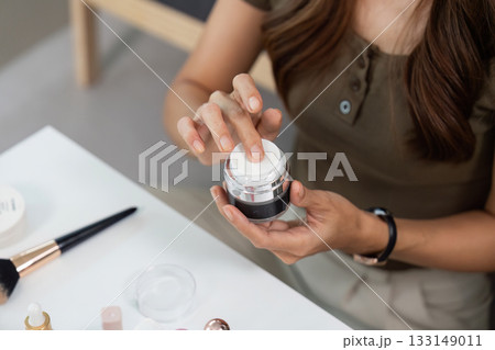 Skincare Routine. Woman applying cream from jar on her hand at home. 133149011