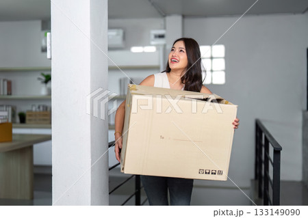Moving house. Woman carrying a box while smiling in her new home. Moving house. Woman carrying a box while smiling in her new home. 133149090
