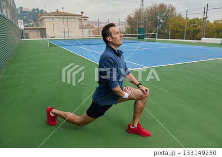 Athlete in Blue Sweatshirt Performing Lunge on Tennis Court for Fitness Training 133149280