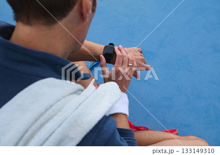 Man Checking Time on Smartwatch at Poolside With Blue Wall in Background Man Checking Time on Smartwatch at Poolside With Blue Wall in Background 133149310