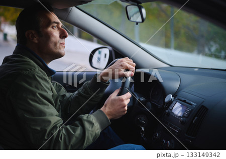 Focused Man Driving Car Interior With Hands On Wheel During Calm Commute 133149342