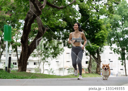 Joyful Woman Running with Corgi in Park Joyful Woman Running with Corgi in Park 133149355