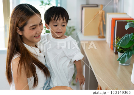Cleaning with Joy. A mother and child engaging in playful cleaning activities at home. 133149366
