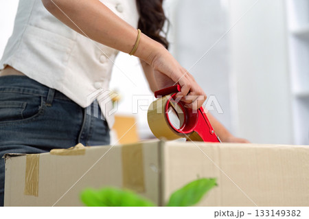 Moving House: Woman Taping Box for a Smooth Transition 133149382