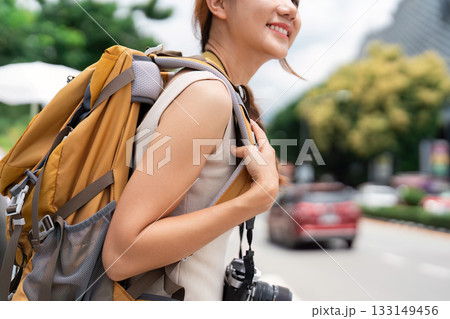Travel. Young woman with backpack smiling on busy city street. 133149456