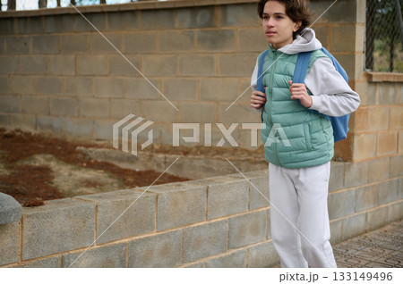 Teen Boy With Backpack Walking By Wall For School, Casual Outdoor Portrait Teen Boy With Backpack Walking By Wall For School, Casual Outdoor Portrait 133149496