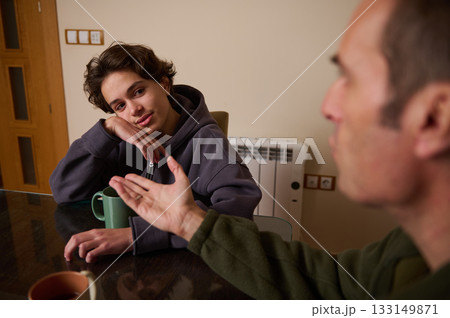 Teenager At Home Having Thoughtful Conversation With Adult At Dining Table 133149871