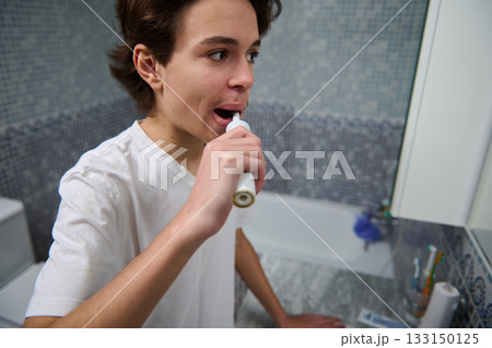 Teenage Boy Brushing Teeth in Bright Bathroom During Morning Routine For Health And Hygiene Everyday Teenage Boy Brushing Teeth in Bright Bathroom During Morning Routine For Health And Hygiene Everyday 133150125