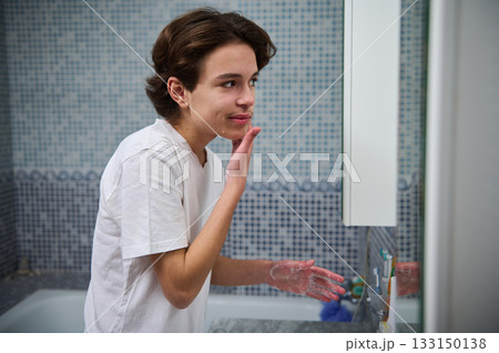 Teenage Boy Washing Face in Bathroom Mirror During Morning Skincare Routine Teenage Boy Washing Face in Bathroom Mirror During Morning Skincare Routine 133150138