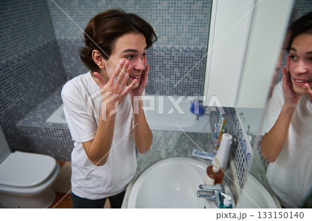 Teenage Boy Enjoys Morning Skincare Routine Reflected in Bathroom Mirror Teenage Boy Enjoys Morning Skincare Routine Reflected in Bathroom Mirror 133150140