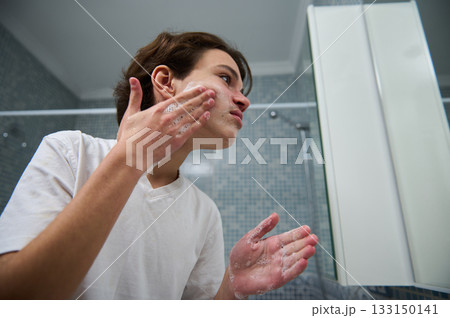 Teen Boy Applies Face Wash In Bathroom For Skincare Routine 133150141