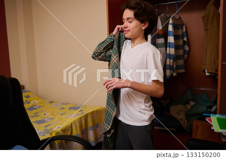 Teenage Boy Folding Clothes in Dorm Room, Casual Moment of Daily Life and Prep Teenage Boy Folding Clothes in Dorm Room, Casual Moment of Daily Life and Prep 133150200