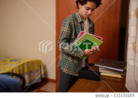 Teenage Boy Organizes Notebooks in Bedroom After School, Preparing for Homework Teenage Boy Organizes Notebooks in Bedroom After School, Preparing for Homework 133150205