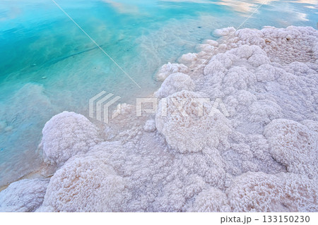 Sand completely covered with crystalline salt on shore of Dead Sea, turquoise blue water near - typical scenery at Ein Bokek beach, Israel 133150230