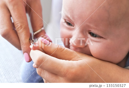 Infant baby boy having his nails cut by mother, detail on scissors and fingertips 133150327