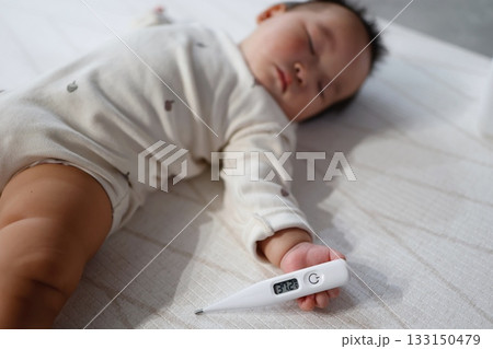 眠る赤ちゃんと体温計の平熱表示37.2度。 133150479
