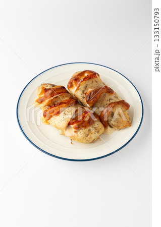 Hasselback chicken breasts baked with tomato and melted cheese on a plate, isolated 133150793