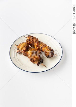 Grilled chicken skewers on a white plate, studio shot of kebab shashlik ready to serve 133150800