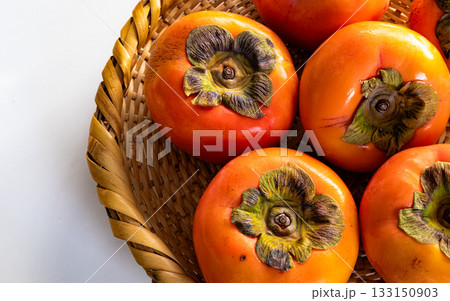 白背景と笊に入った真っ赤な柿 133150903