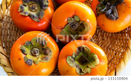 白背景と笊に入った真っ赤な柿 133150904