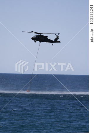 Bucket carrying helicopter.a helicopter scoops up water from the sea. High quality photo 133151241
