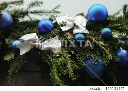 Silver bow on a Christmas tree branches with blue balls Silver bow on a Christmas tree branches with blue balls 133151375