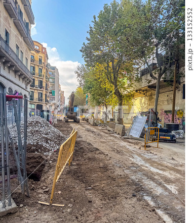Urban street reconstruction site with excavator, dirt road, and safety barriers. Infrastructure maintenance and civil engineering concept. High quality photo Urban street reconstruction site with excavator, dirt road, and safety barriers. Infrastructure maintenance and civil engineering concept. High quality photo 133152552