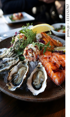 Elegant seafood plate featuring fresh oysters, grilled shrimp, mussels and delicate smoked salmon. Chilled on ice with lemon and arugula. Dish for seafood lovers and gourmet food content 133152767