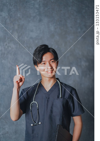 スクラブを着て指差しポーズをする若い男性医師 133153471