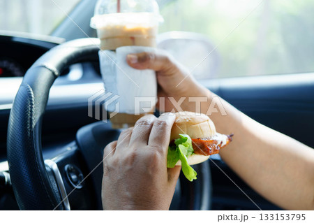 Asian woman driver hold and eat hamburger food in car. 133153795