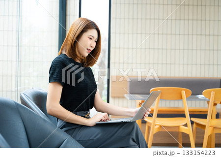 Asian businesswoman calculates finances on a clipboard with calculator by her laptop and smartphone in office Asian businesswoman calculates finances on a clipboard with calculator by her laptop and smartphone in office 133154223