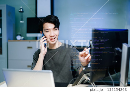 Asian software developer working late with code on screens, tablet, and phone. Concept of programming, tech lifestyle, 133154268
