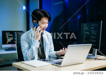Asian software developer working late with code on screens, tablet, and phone. Concept of programming, tech lifestyle, 133154323