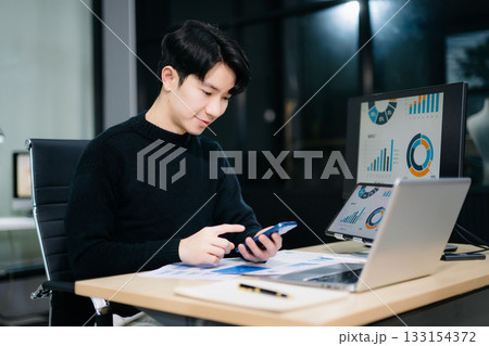 Asian man using laptop and tablet while sitting at her working place. Concentrated at work. Asian man using laptop and tablet while sitting at her working place. Concentrated at work. 133154372