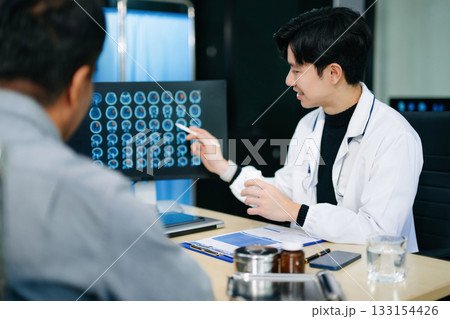 Friendly doctor discussing brain scan results with patient on screen. Health consultation, neurology, diagnosis, and care in clinic Friendly doctor discussing brain scan results with patient on screen. Health consultation, neurology, diagnosis, and care in clinic 133154426