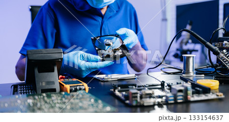 Hard disk drive on the technician's desk and a computer motherboard as a component. the concept of data, hardware 133154637