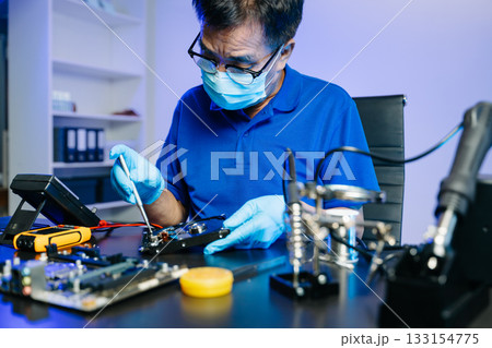 Skilled technician in lab coat and gloves recovers data from hard disk. 133154775