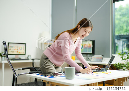 woman celebrates success while working on a tablet in a modern creative office, capturing achievement 133154781