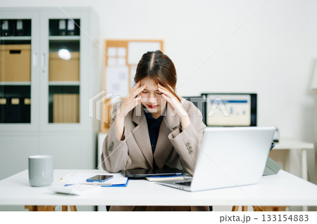 Young woman overwhelmed and exhausted at her desk in modern office. Struggling with stress, deadlines, and data reports. Young woman overwhelmed and exhausted at her desk in modern office. Struggling with stress, deadlines, and data reports. 133154883